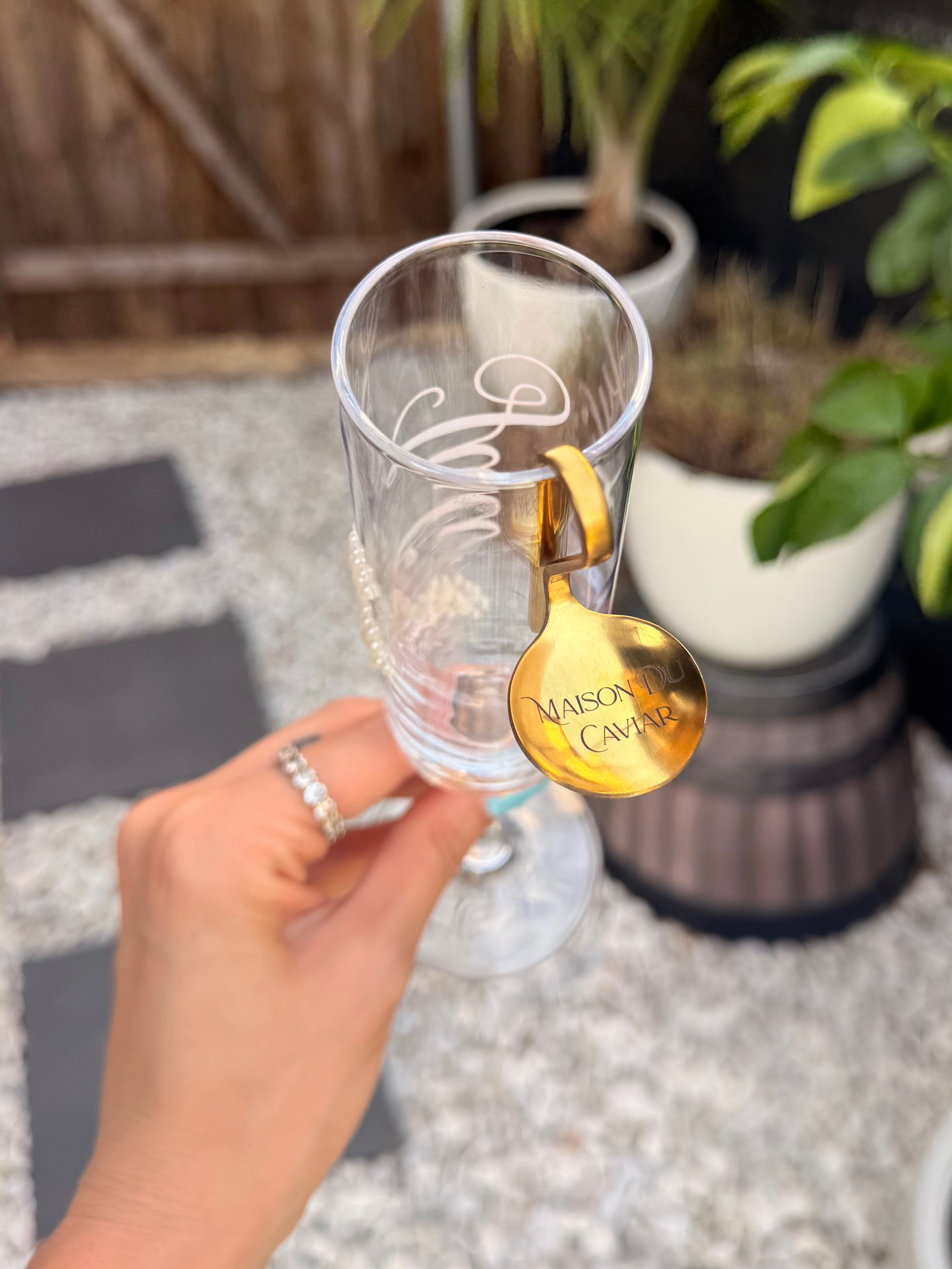 Custom engraved champagne flute with a gold caviar spoon charm, engraved for Maison Du Caviar